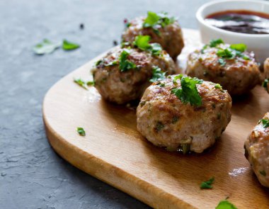 Soslu, baharatlı ve sarımsaklı ahşap bir tahtada sergilenen baharatlı köfteler. Kopyalama alanı olan yan görünüm.