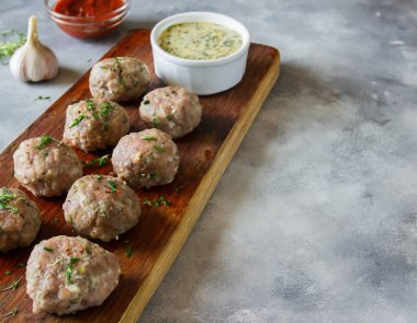 Soslu, baharatlı ve sarımsaklı ahşap bir tahtada sergilenen baharatlı köfteler. Kopyalama alanı olan yan görünüm.