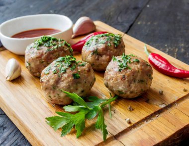 Soslu, baharatlı ve sarımsaklı ahşap bir tahtada sergilenen baharatlı köfteler. Kopyalama alanı olan yan görünüm.