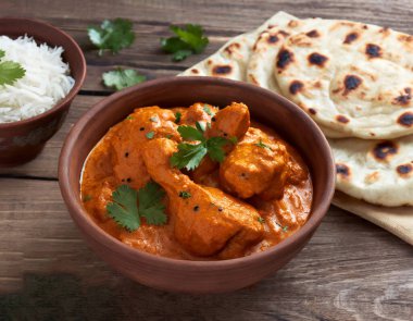 Baharatlı tavuk tikka masala kil tabakta servis edilir pirinç ve ahşap zemin üzerinde naan ekmeği.