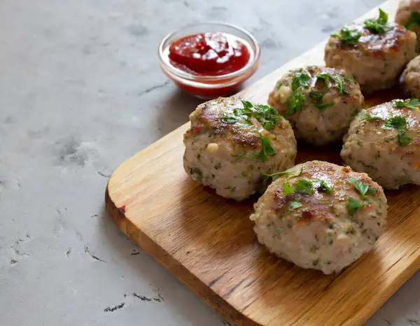 Soslu, baharatlı ve sarımsaklı ahşap bir tahtada sergilenen baharatlı köfteler. Kopyalama alanı olan yan görünüm.