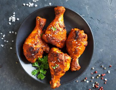 Üst manzara, Hint usulü tandır tavuğu koyu taştan bir arka planda sunuluyor. Tavuk bacakları yoğurt ve baharatla marine edilmiş..