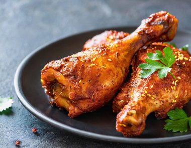 Üst manzara, Hint usulü tandır tavuğu koyu taştan bir arka planda sunuluyor. Tavuk bacakları yoğurt ve baharatla marine edilmiş..