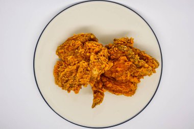 Kızarmış tavuk ve sebzeler beyaz tabakta.