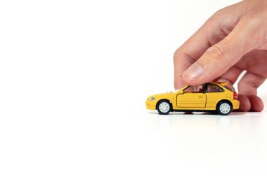 Beyaz arka planda izole edilmiş sarı bir oyuncak araba tutuyordu. Bazı düzenlemelerden sonra.