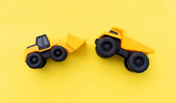 Miniature wheel loader and dump truck isolated on yellow background. After some edits.