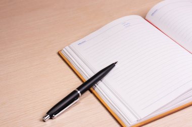 Masanın üzerinde açık bir kitap ve kalem. Bazı düzenlemelerden sonra.