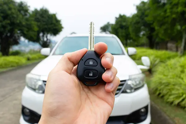Car key in hand with car on the background. Car stuff concept. After some edits.