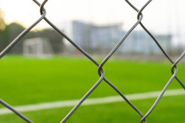 Çitin dışından futbol sahası görünüyor, çitlere odaklanıyor. Bazı düzenlemelerden sonra.