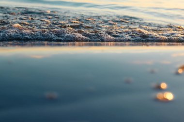 Batan güneşin yansımasındaki deniz dalgaları. Dalgalar deniz kıyısına vuruyor. Yaklaş.