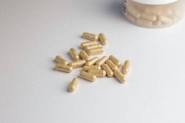 Beyaz arka planda bej tozlu vitamin kapsülleri. Biyolojik olarak aktif katkı maddeleri