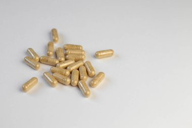 Beyaz arka planda bej tozlu vitamin kapsülleri. Biyolojik olarak aktif katkı maddeleri