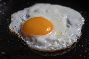 Kızarmış yumurta. Güneşli tarafı kızartma tavasında pişiyor. Yakın plan. Hızlı ve besleyici bir kahvaltı..