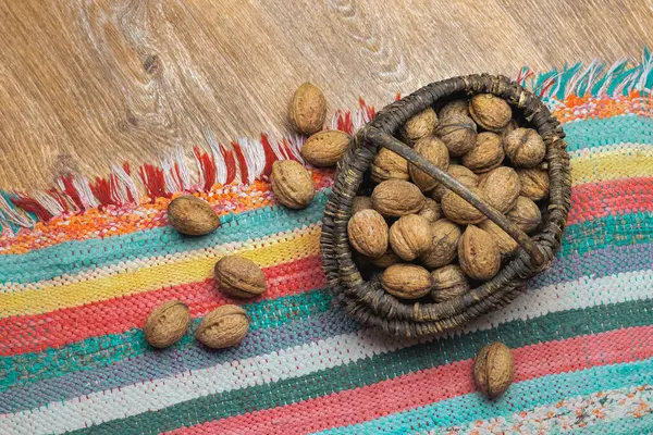 Yerde ceviz ve el yapımı halı olan hasır sepet.