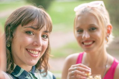 Parkta gülümseyen ve poz veren iki arkadaş..