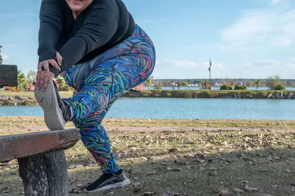 年轻的胖女人在湖边的公园里伸腿 — 图库照片