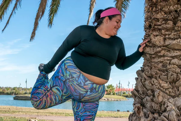 年轻的胖女人在湖边的公园里伸腿 — 图库照片