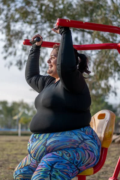 年轻的胖女人在湖边的公园里做肩膀运动 — 图库照片