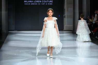 Toronto, ON, Canada - December 7, 2024: A model walks the runway at the Milana Loren Couture collection during the Toronto Kids Fashion Week fashion show. clipart