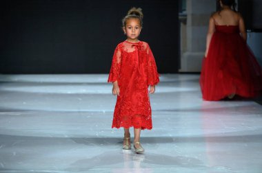 Toronto, ON, Canada - December 7, 2024: A model walks the runway at the Milana Loren Couture collection during the Toronto Kids Fashion Week fashion show. clipart