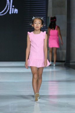 Toronto, ON, Canada - December 7, 2024: A model walks the runway at the Little Olin collection during the Toronto Kids Fashion Week fashion show. clipart