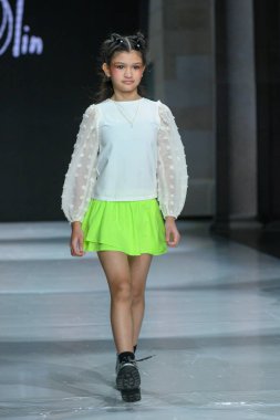 Toronto, ON, Canada - December 7, 2024: A model walks the runway at the Little Olin collection during the Toronto Kids Fashion Week fashion show. clipart