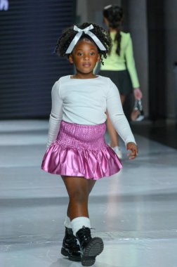 Toronto, ON, Canada - December 7, 2024: A model walks the runway at the Little Olin collection during the Toronto Kids Fashion Week fashion show. clipart