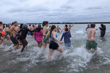 Toronto, ON, Kanada 1 Ocak 2025: Toronto Kutup Ayısı Dalışı sırasında Sunnyside Sahili 'ndeki Ontario Gölü' nün soğuk sularına (+ 3) akın eden insanlar..