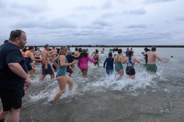 Toronto, ON, Kanada 1 Ocak 2025: Toronto Kutup Ayısı Dalışı sırasında Sunnyside Sahili 'ndeki Ontario Gölü' nün soğuk sularına (+ 3) akın eden insanlar..