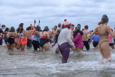 Toronto, ON, Kanada 1 Ocak 2025: Toronto Kutup Ayısı Dalışı sırasında Sunnyside Sahili 'ndeki Ontario Gölü' nün soğuk sularına (+ 3) akın eden insanlar..