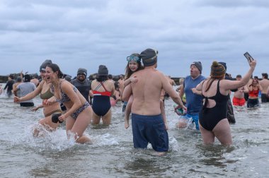 Toronto, ON, Canada  January 1, 2025: People are seen in the frigid waters (+3C) of Lake Ontario at Sunnyside Beach during the Toronto Polar Bear Dip. clipart