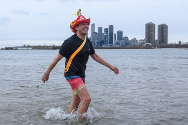 Toronto, ON, Canada  January 1, 2025: People are seen in the frigid waters (+3C) of Lake Ontario at Sunnyside Beach during the Toronto Polar Bear Dip. clipart