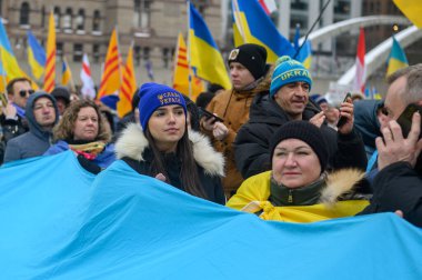 Toronto, ON, Kanada 23 Şubat 2025: Rusya 'nın Ukrayna' yı tam ölçekli işgalinin 3. yıldönümünde Nathan Phillips Meydanı 'nda insanlar büyük bir bayrak taşıyor..