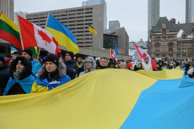Toronto, ON, Kanada 23 Şubat 2025: Rusya 'nın Ukrayna' yı tam ölçekli işgalinin 3. yıldönümünde Nathan Phillips Meydanı 'nda insanlar büyük bir bayrak taşıyor..