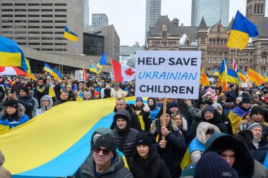 Toronto, ON, Kanada 23 Şubat 2025: Göstericiler, Rusya 'nın Ukrayna' yı tam ölçekli işgalinin 3. yıldönümünde Nathan Phillips Meydanı 'nda düzenlenen gösterinin bayrağını taşıyor..