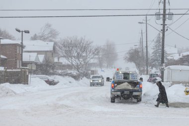 Toronto, ON, Kanada - 27 Şubat 2025: Karlı bir cadde tuğla binalar ve çıplak ağaçlarla dolu bir yerleşim alanından geçiyor.