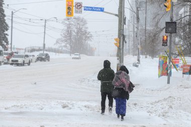 Toronto, ON, Kanada - 27 Şubat 2025: Kar fırtınası sırasında yayalar karlı bir cadde boyunca yürür.
