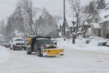 Toronto, ON, Kanada - 27 Şubat 2025: Kar küreme aracı kar fırtınası sırasında yolu temizliyor.
