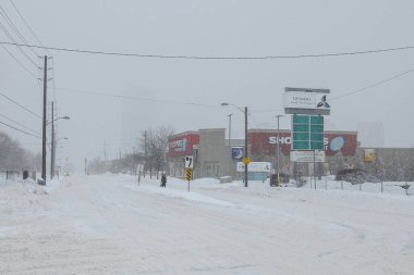 Toronto, ON, Kanada - 27 Şubat 2025: Karlı bir cadde tuğla binalar ve çıplak ağaçlarla dolu bir yerleşim alanından geçiyor.