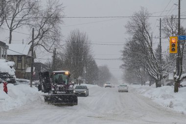 Toronto, ON, Kanada - 27 Şubat 2025: Kar küreme aracı kar fırtınası sırasında yolu temizliyor.