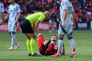 Toronto, ON, Kanada - 15 Mart 2025: Hakem Allen Chapman, BMO Field 'da Chicago Fire FC' ye karşı oynanan bir maç sırasında Toronto FC 'de yerde yatan bir oyuncuyu kontrol ediyor. Sayı 1: 2, Chicago İtfaiyesi kazandı.)