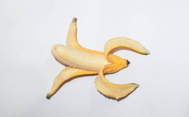 Beyaz arka planda yarısı soyulmuş olgun bir muz. Sarı muz meyvesi, sağlıklı bir yaz atıştırması.