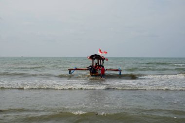 Old boat with local men moving by sea at daytime, perahu nelayan di pinggir pantai Widuri Pemalang, Indonesia, digunakan untuk angkutan wisata laut, wisatawan diajak naik perahu ke tengah laut, ombaknya kecil, resiko kecil membayar sejumlah uang 