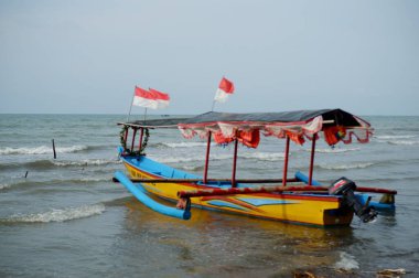 Old boat parked on beach with local people, daytime view , perahu nelayan di pinggir pantai Widuri Pemalang, Indonesia, digunakan untuk angkutan wisata laut, wisatawan diajak naik perahu ke tengah laut, ombaknya kecil, resiko kecil membayar uang