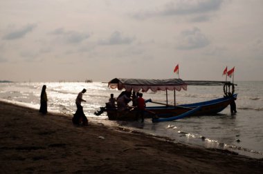 Old boat with local men moving by sea at daytime, perahu nelayan di pinggir pantai Widuri Pemalang, Indonesia, digunakan untuk angkutan wisata laut, wisatawan diajak naik perahu ke tengah laut, ombaknya kecil, resiko kecil membayar sejumlah uang 