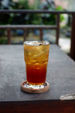 Glass of refreshing cold tea with ice cubes served in glass on table, es teh minuman pavorit orang indonesia, olahan teh dicampur dengan es batu disajikan dengan gelas ukuran besar, warna nya coklat bening, cantik, rasanya manis dan segar  