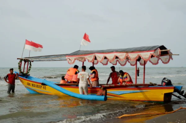 Old boat with local men moving by sea at daytime, perahu nelayan di pinggir pantai Widuri Pemalang, Indonesia, digunakan untuk angkutan wisata laut, wisatawan diajak naik perahu ke tengah laut, ombaknya kecil, resiko kecil membayar sejumlah uang 