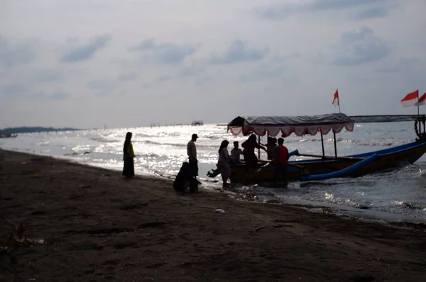 Old boat with local men moving by sea at daytime, perahu nelayan di pinggir pantai Widuri Pemalang, Indonesia, digunakan untuk angkutan wisata laut, wisatawan diajak naik perahu ke tengah laut, ombaknya kecil, resiko kecil membayar sejumlah uang 