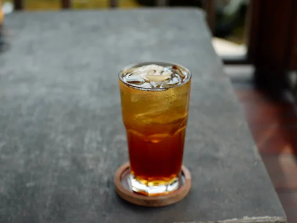Glass of refreshing cold tea with ice cubes served in glass on table, es teh minuman pavorit orang indonesia, olahan teh dicampur dengan es batu disajikan dengan gelas ukuran besar, warna nya coklat bening, cantik, rasanya manis dan segar 