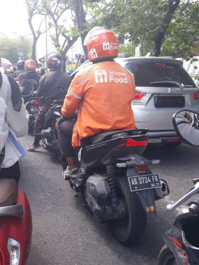 the motorcycles stopped at red light, sepeda motor ojek online gojek berhenti dan lewat di jalanan kota yogyakarta, mencari penumpang membantu bepergian dengan tekhnologi online daring smartphone dengan sepeda motor shopee